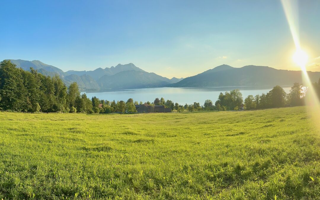 Sonnenuntergang über einem stillen See mit Bergen im Hintergrund – Symbol für Ruhe, Naturverbundenheit und achtsame Erholung